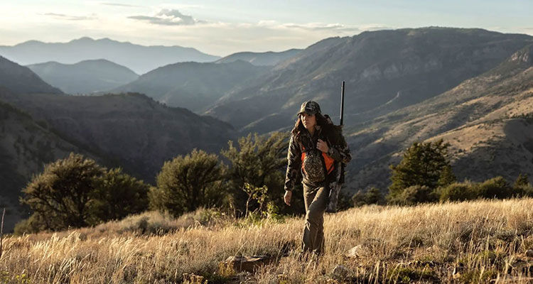 hunter walking in front of mountains