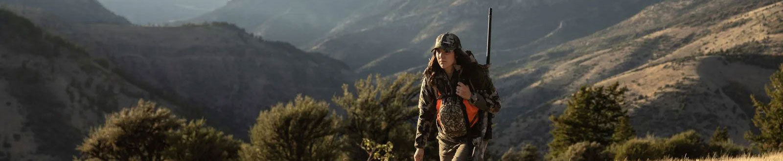 hunter walking in front of mountains