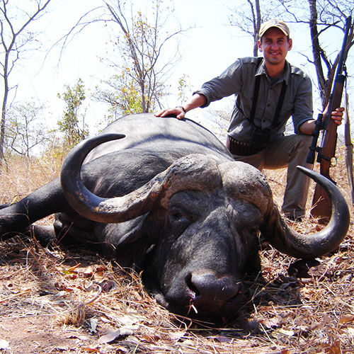 Jon Langenfeld kneeling next to a water buffalo